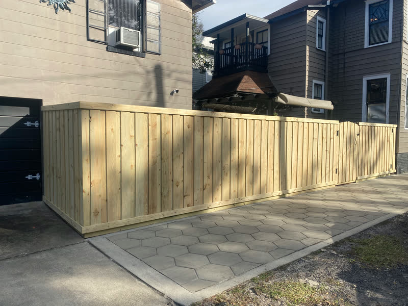 New board on board privacy fence with a cap rail wrapping a driveway corner beside a two story home