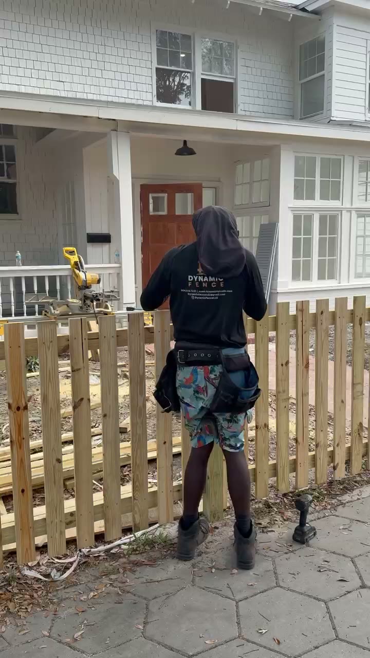 Dynamic Fence crew member installing an open picket fence beside a historic home