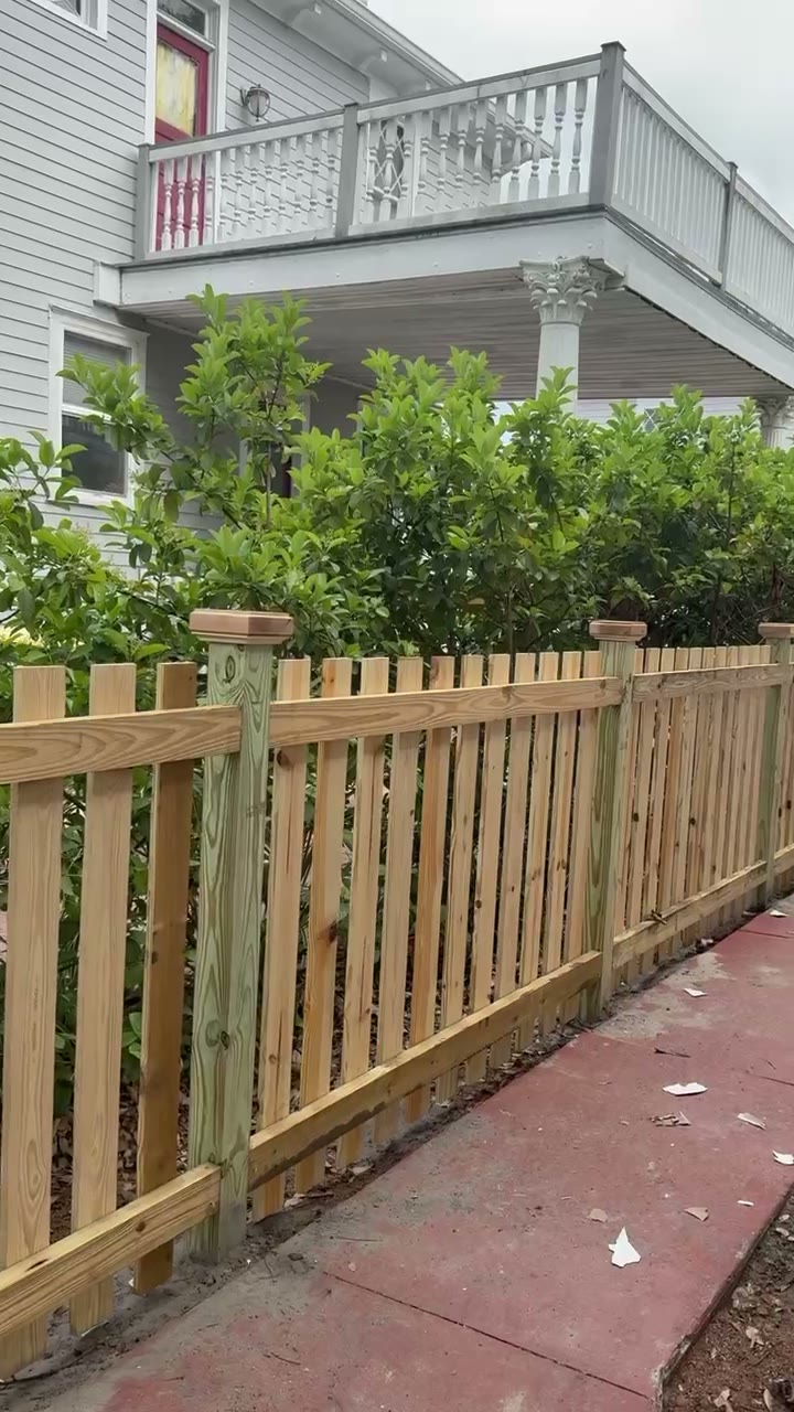 Open picket fence in front of a two story Victorian style home