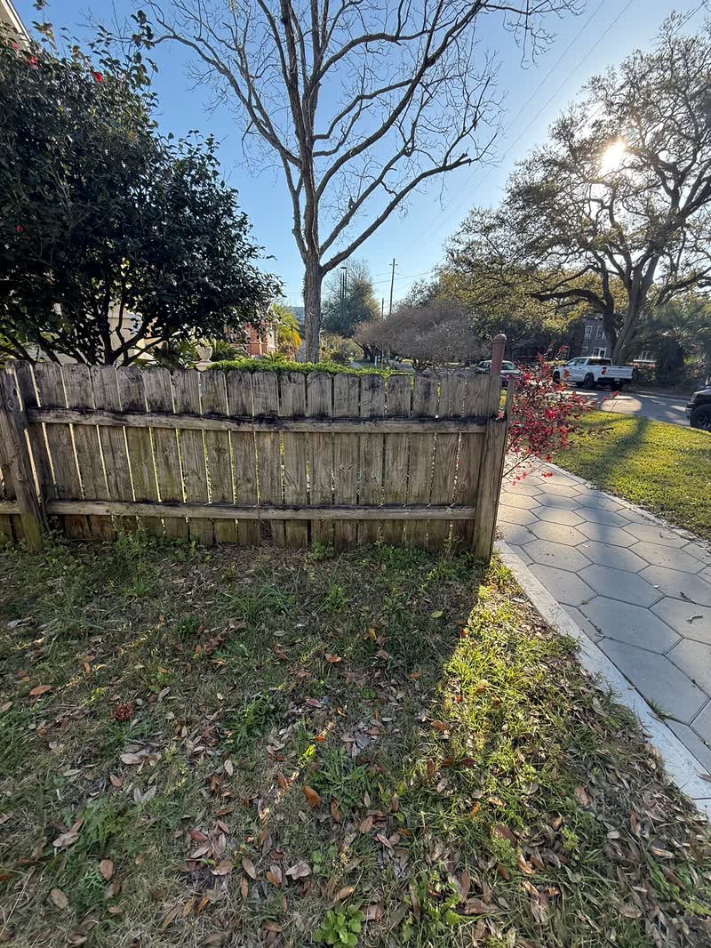 Sagging, rot stained picket fence along a sidewalk before replacement