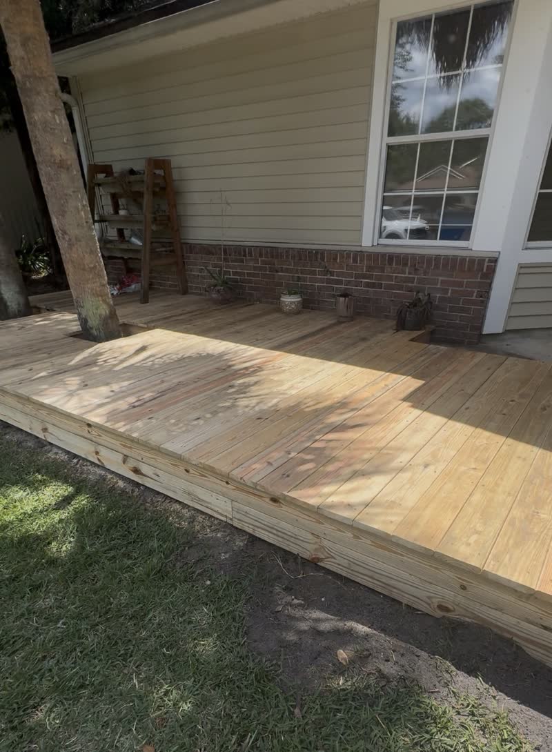 New pressure treated wooden deck built onto a brick front porch